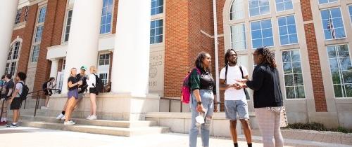 Students talking in small groups outside the library between classes